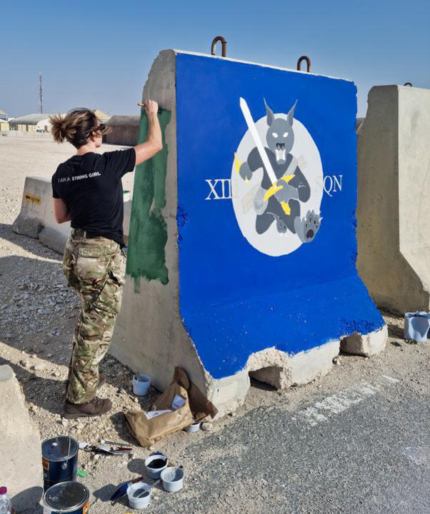 Image shows servicewoman painting a blast wall.